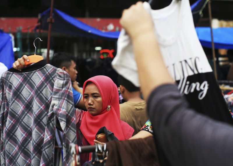 Seorang wanita memilih pakaian bekas di sebuah pasar baju bekas di Jakarta. Foto Reuters/Beawiharta. 
