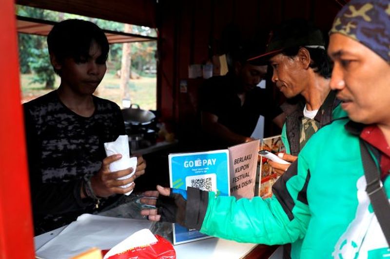 Driver Gojek memproses pesanan makanan di sebuah warung. Foto Reuters.