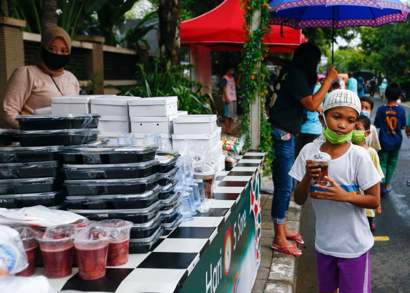 Seorang anak menerima makanan untuk berbuka puasa yang dibagikan secara gratis saat Ramadan di Jakarta, 15 April 2021. Foto Reuters/Ajeng Dinar Ulfiana.