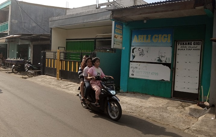 Warga melintas menggunakan sepeda motor di depan sebuah kios tukang gigi di kawasan Benda, Tangerang, Banten, Senin (28/3). Alinea.id/Kudus Purnomo Wahidin