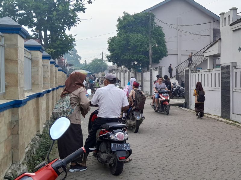 Beberapa orang tua tengah mengantar anaknya yang bersekolah di SMAN 15 Jalan Raya Korelet, Kabupaten Tangerang, Banten, menggunakan sepeda motor, Rabu (8/3/2023). Alinea.id/Akbar Ridwan