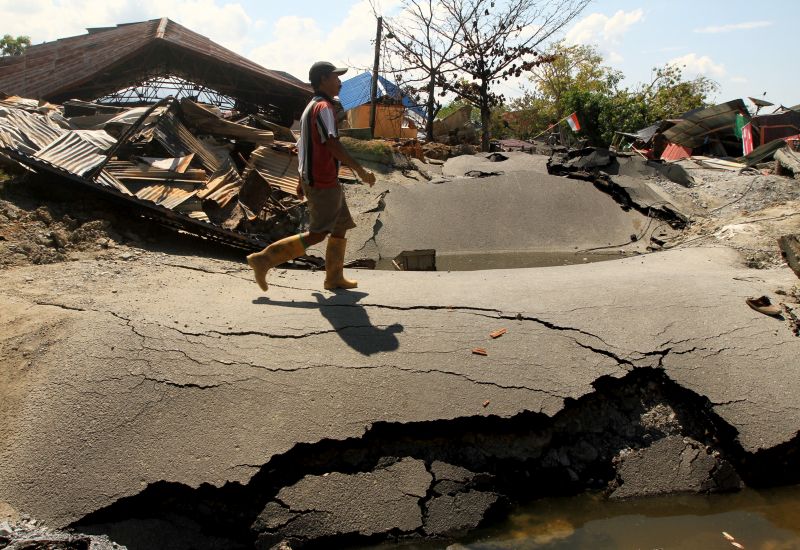 Seorang warga berjalan di dekat rumah-rumah yang rusak berat dan jalanan yang terbelah akibat gempa di Petobo, Palu Selatan, Sulawesi Tengah, Senin (1/10/2018)./Foto Antara/Akbar Tado
