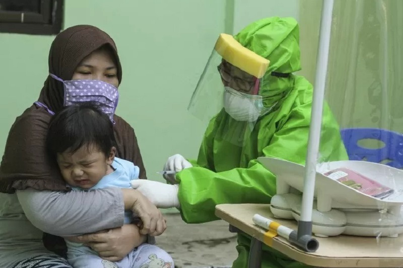 Seorang dokter mengenakan alat pelindung diri (APD) saat melakukan imunisasi kepada anak di Puskesmas Cisalak Pasar, Depok, Jawa Barat, Rabu (24/6/2020)./Foto Antara/Asprolla Dwi Adha.