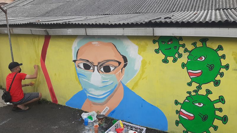 Seorang pemuda RT 03 RW 03, Kelurahan Cilangkap, Kecamatan Cipayung, Jakarta Timur tengah menyelesaikan mural di tembok warga yang ada di Gang Darusalam, Jakarta Timur, Minggu (30/5/2021). Alinea.id/Achmad Al Fiqri.