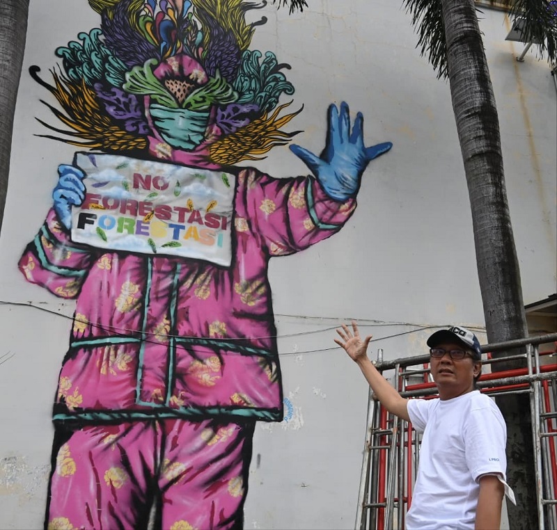 Kurator Bambang Asrini Widjanarko menunjuk mural karya Anagard. Foto dokumentasi L Project.