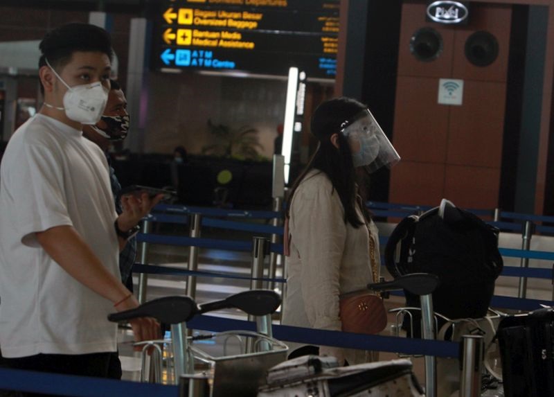 Calon penumpang pesawat menggunakan pelindung wajah dan sarung tangan karet saat mengantre untuk lapor diri di Terminal 3 Bandara Soekarno Hatta, Tangerang, Banten, Minggu (10/5/2020). Foto Antara/Muhammad Iqbal.