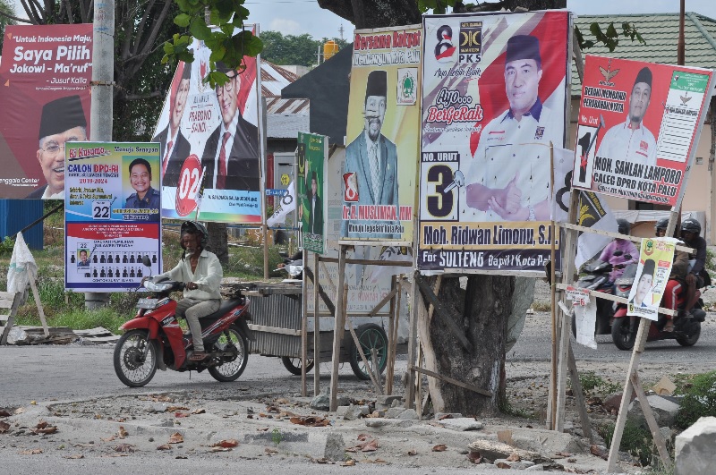 Pengendara melintas di sekitar jejeran APK peserta Pemilu 2019 yang terpasang pada sisi jalan di Palu, Sulawesi Tengah, Kamis (11/4/2019). /Foto Antara