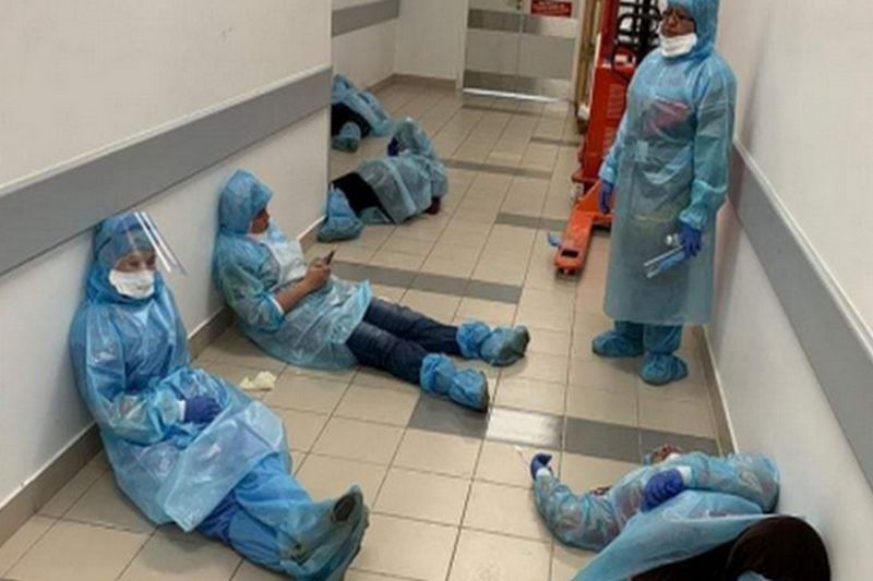 Masih mengenakan baju hazmat, sejumlah tenaga kesehatan beristirahat di koridor rumah sakit di sela-sela tugas. /Foto Twitter