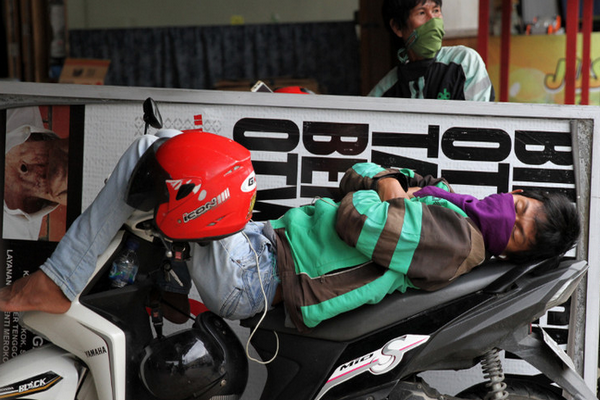 Pengemudi ojek daring tertidur di atas sepeda motornya akibat sepinya orderan di Kota Kendari, Sulsel, Rabu (8/4/2020). /Foto Antara