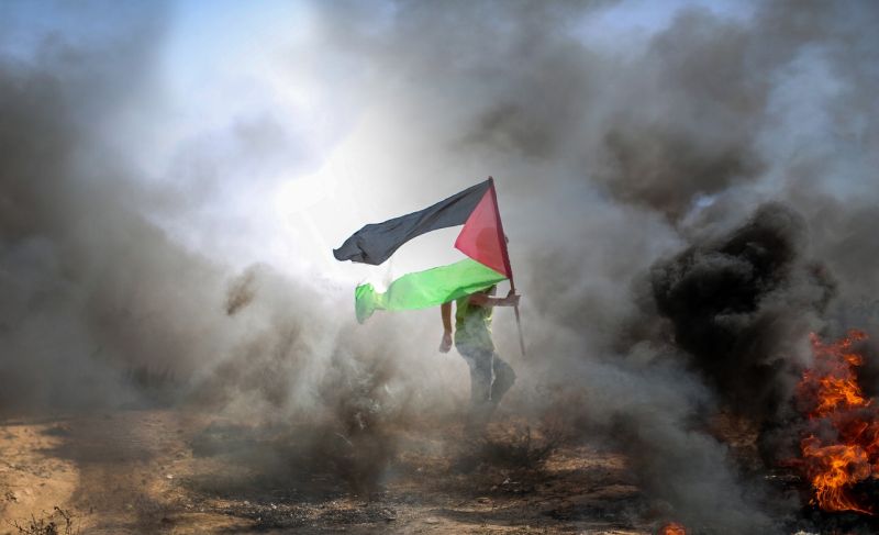 Seorang pria membawa bendera Palestina di tengah gempuran. ./Foto Hosny Salah/Pixabay.com