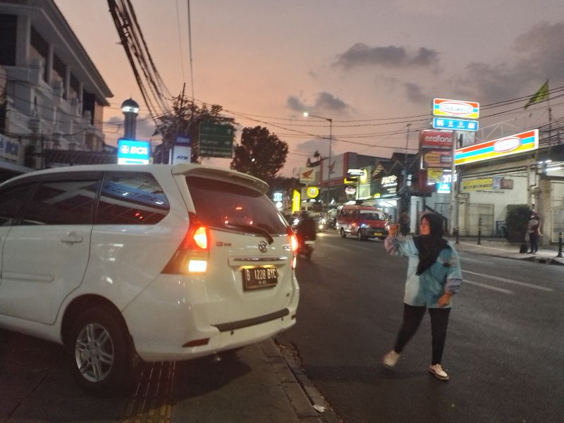 Juru parkir perempuan, Sinta, tengah memandu pengendara mobil yang keluar dari halaman parkir sebuah kantor koperasi di Jalan Raya Ragunan, Jakarta Selatan , Kamis (12/10/2023). Alinea.id/Ummu Hafifah 