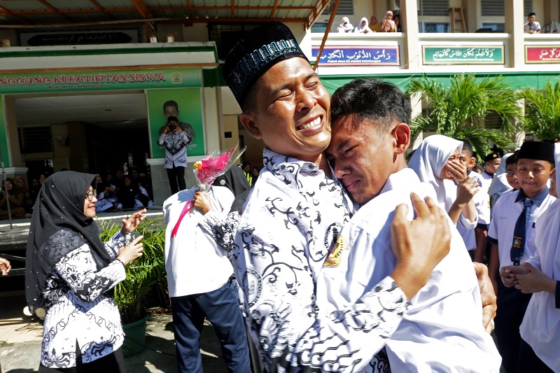 Seorang pelajar memberikan ucapan selamat dengan memeluk gurunya usai upacara peringatan hari guru nasional dan HUT PGRI di MTsN Model, Banda Aceh, Aceh, Senin (25/11/2019)./Foto Antara/Irwansyah Putra